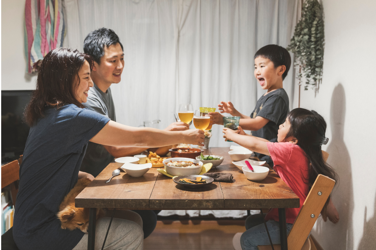 食卓を囲んで笑顔で乾杯する家族。AIとの付き合い方を考える中で、人と人との温かいつながりを大切にする家庭のイメージ。